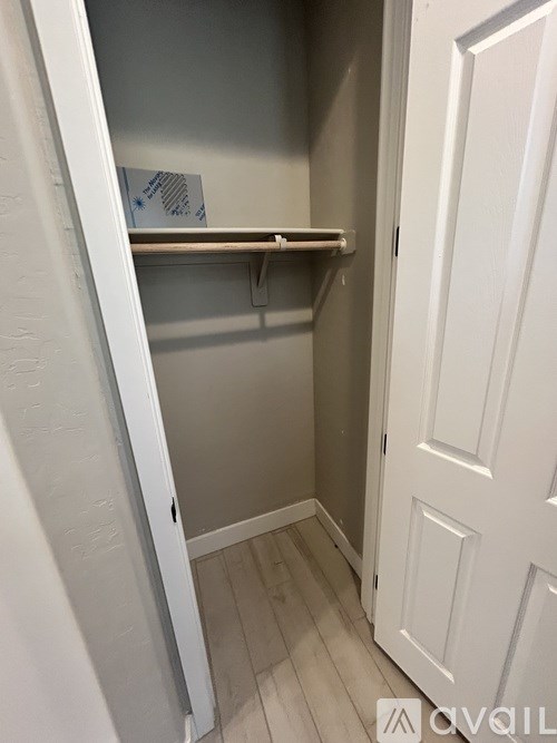 A white door is open to a small pantry with a shelf and a card on the wall.