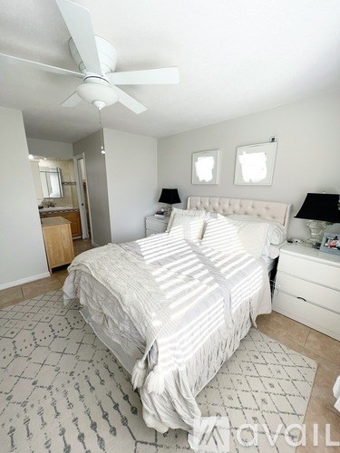 A bedroom with a large bed, a ceiling fan, and a rug on the floor.