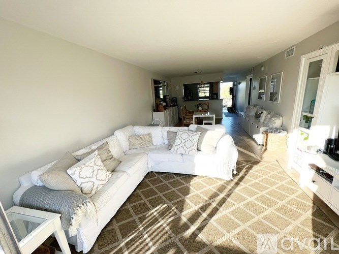 A living room with a white couch and a brown patterned rug.