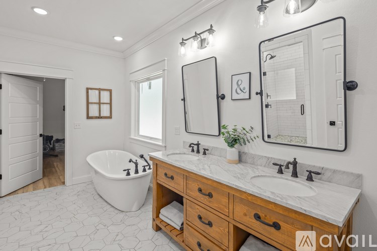 A bathroom with a white tub, sink, and mirror.