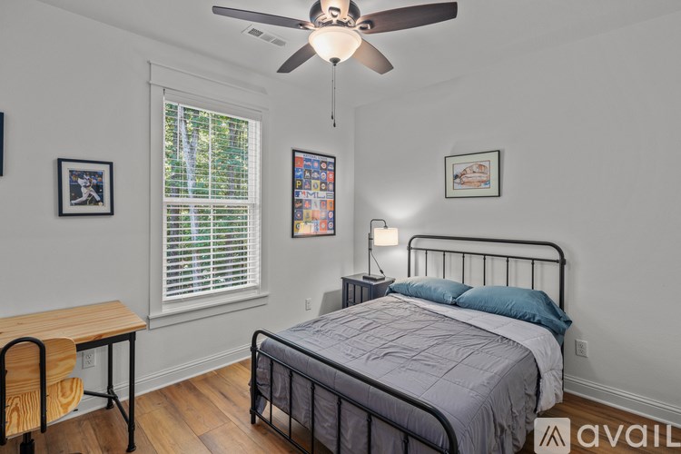 A bedroom with a bed, a desk, and a ceiling fan.