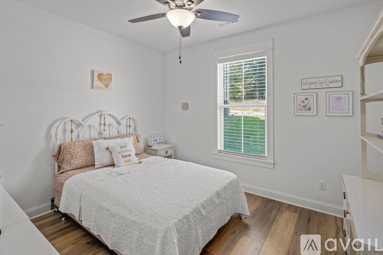 A bedroom with a bed, a ceiling fan, and a window with blinds.