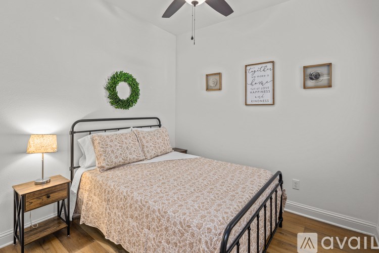 A bedroom with a bed, a wreath, a lamp, and a wall hanging.