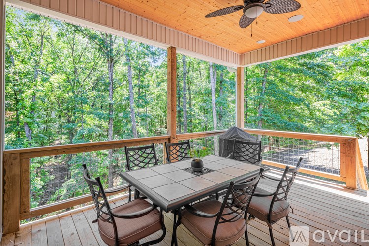 A table with chairs is on a deck with a forest view.