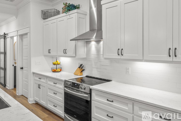 A kitchen with white cabinets and a stainless steel range hood.