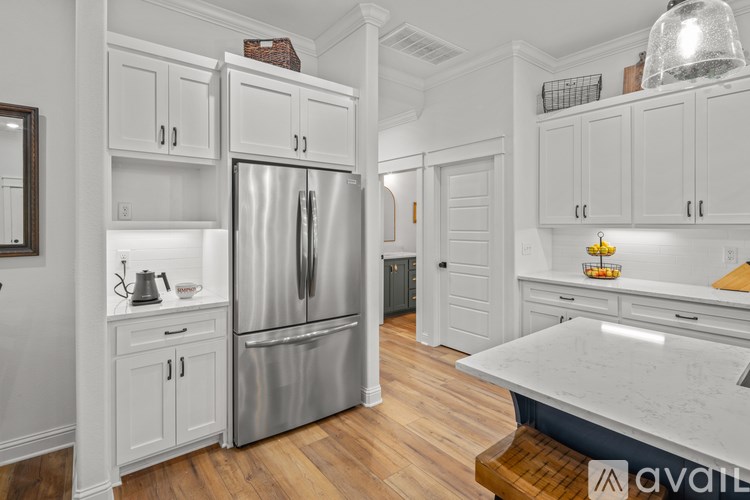 A kitchen with a stainless steel refrigerator and white cabinets.