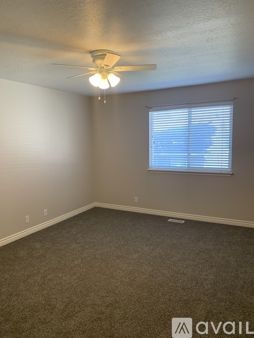 A room with a ceiling fan and a window with blinds.