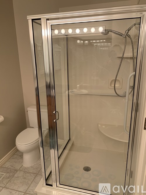 A bathroom with a toilet, a walk-in shower with a glass door, and a tiled floor.