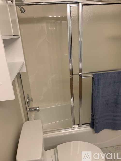 A toilet in a bathroom with a glass shower door.