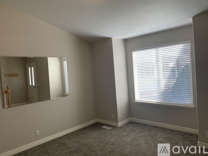 A room with a large mirror and a window with blinds.