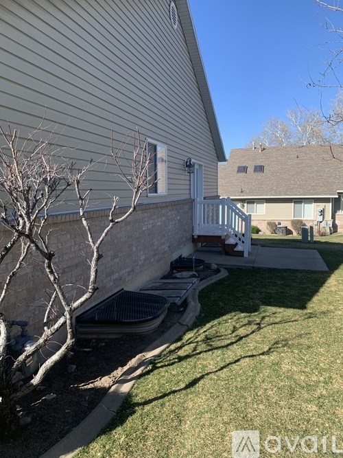 A house with a well-kept lawn and a tree with no leaves.