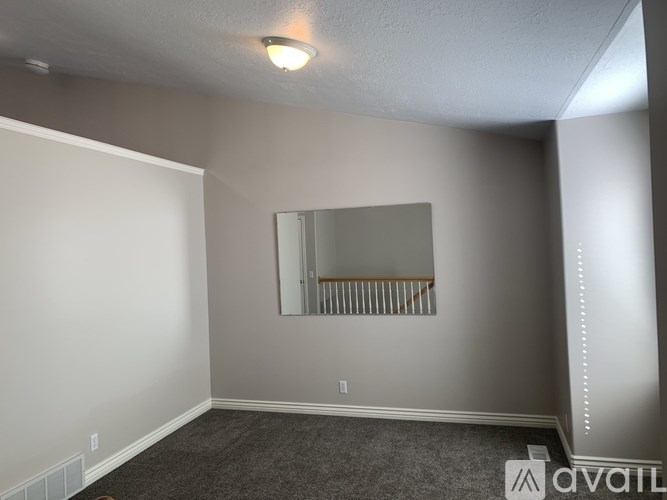 A room with a grey carpet and a mirror on the wall.