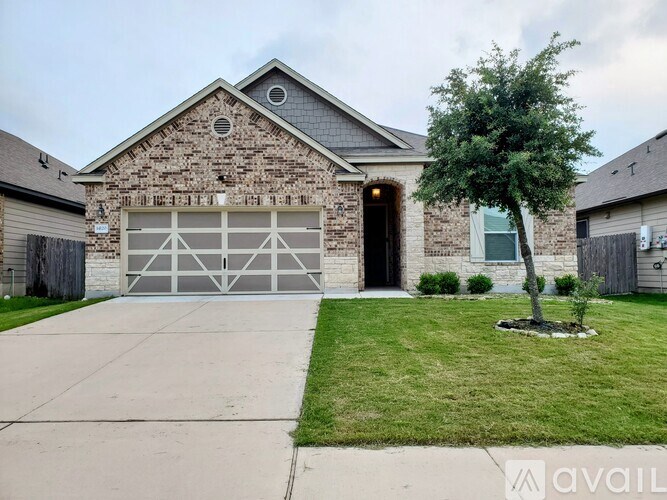 A house with a garage and a tree in front.