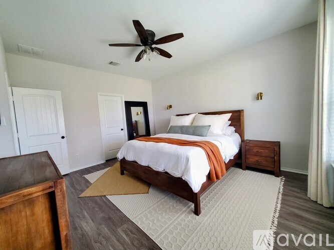 A bedroom with a bed, dresser, and ceiling fan.