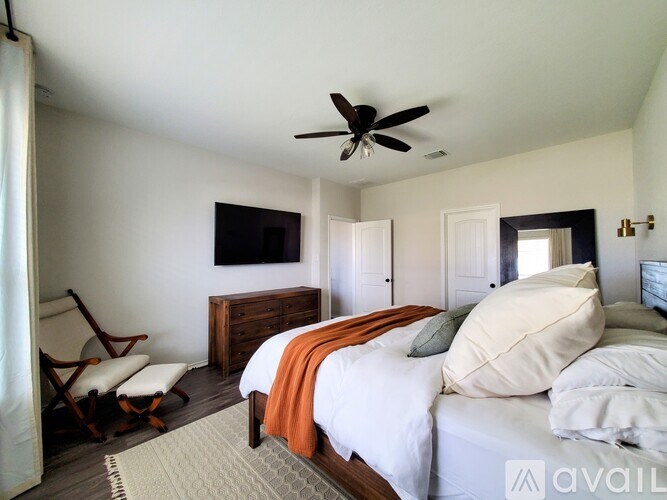 A bedroom with a bed, chair, and a ceiling fan.