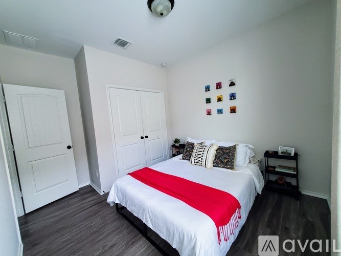A bedroom with a bed, pillows, and a red and white blanket.