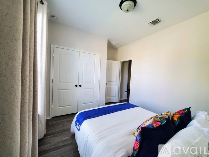 A bedroom with a bed, two doors, and a window with curtains.