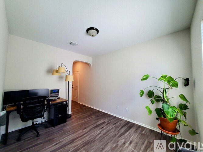 A room with a desk, chair, and a potted plant.