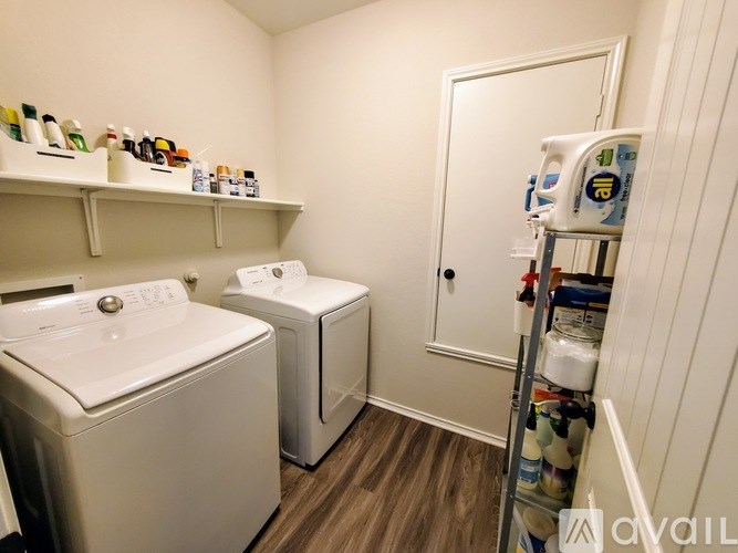A small laundry room with a washer and dryer and a shelf with cleaning products.