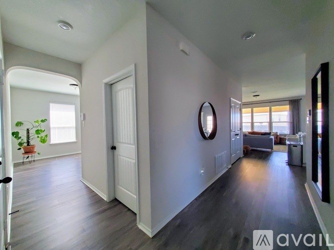 A long hallway with a mirror on the wall and a door at the end.