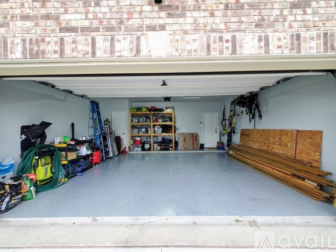 A garage with a brick wall above and a ladder, shelves, and tools inside.