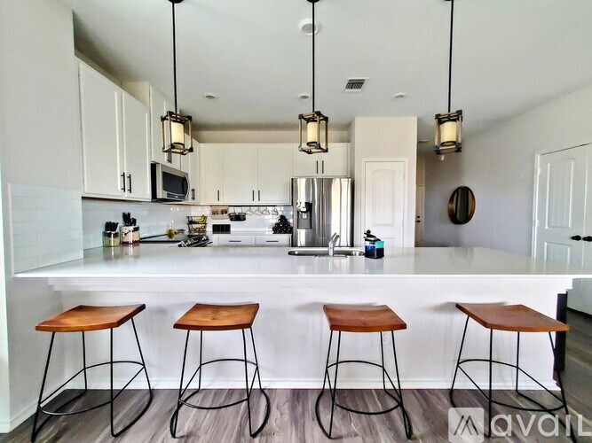 A kitchen with white cabinets and a white countertop with a bar stool in front of it.