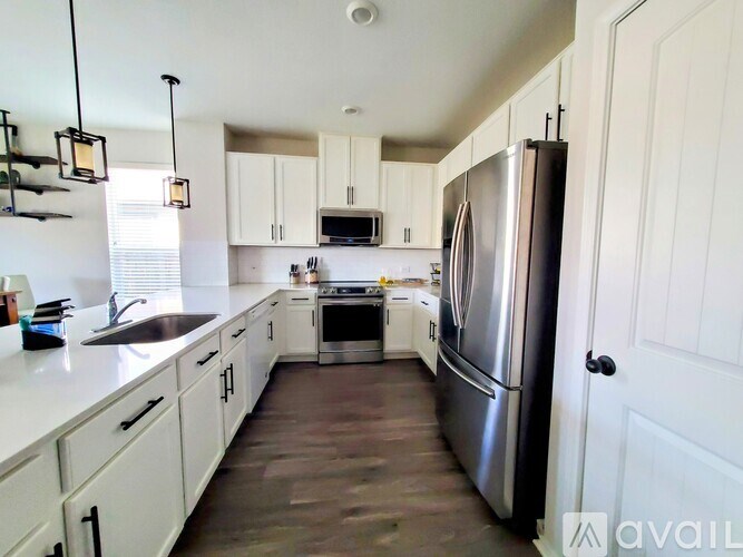 A kitchen with white cabinets and a stainless steel refrigerator.