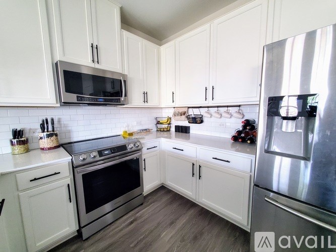 A kitchen with white cabinets and a stainless steel refrigerator.