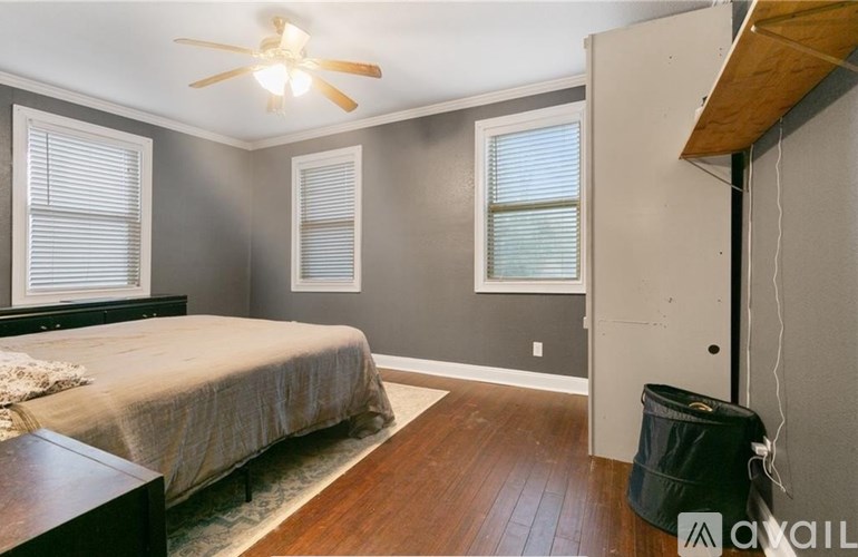 A bedroom with a bed, a ceiling fan, and a window with blinds.