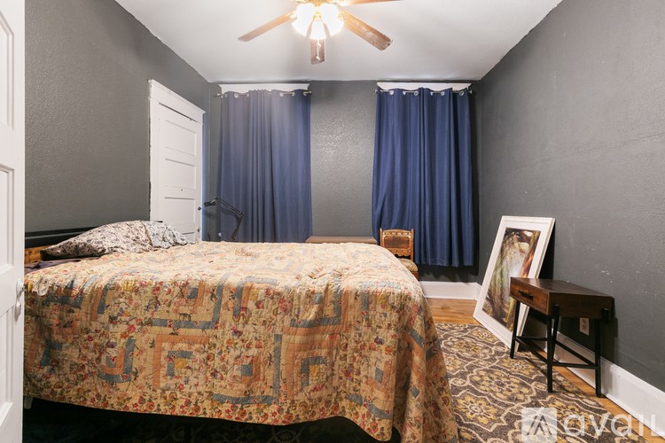 A bedroom with a bed, a ceiling fan, and a picture frame on a small table.