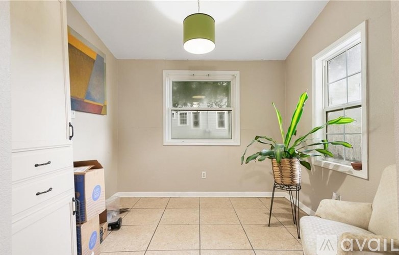 A room with a white couch, a plant, and a painting on the wall.