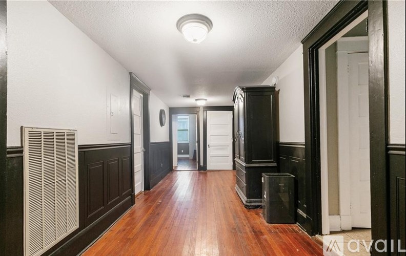 A long hallway with wood floors and white walls.