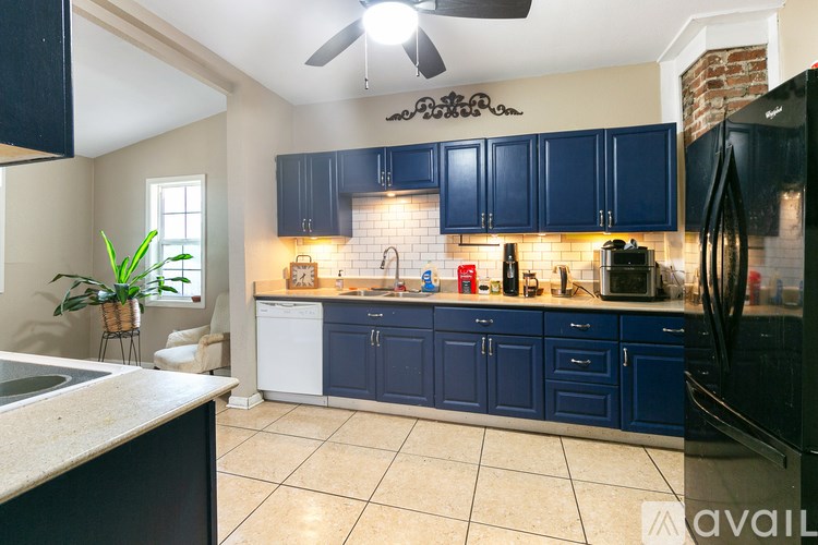 A kitchen with blue cabinets and a black refrigerator.