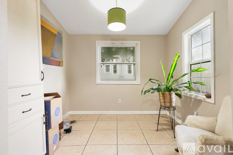A room with a white couch and a plant on a table.