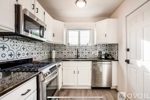 A kitchen with a black stove top oven and a black microwave above a white counter.