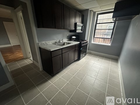 A kitchen with black cabinets and a white sink.