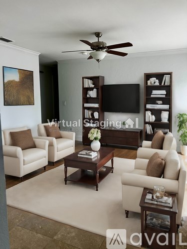 A living room with a ceiling fan and a television on a stand.
