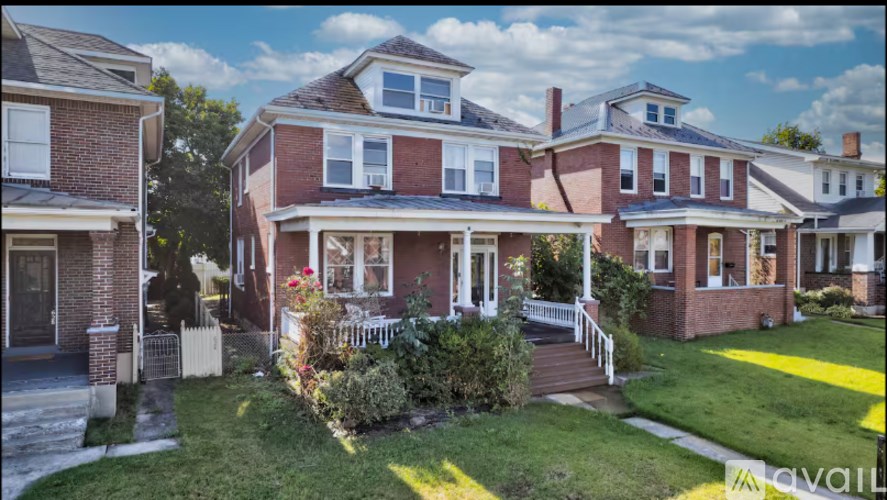 A large red brick house with a white picket fence in front.