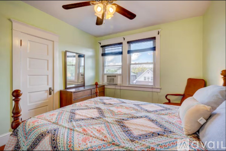 A bedroom with a bed, chair, and window.