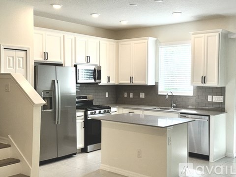 A kitchen with white cabinets and a stainless steel refrigerator.