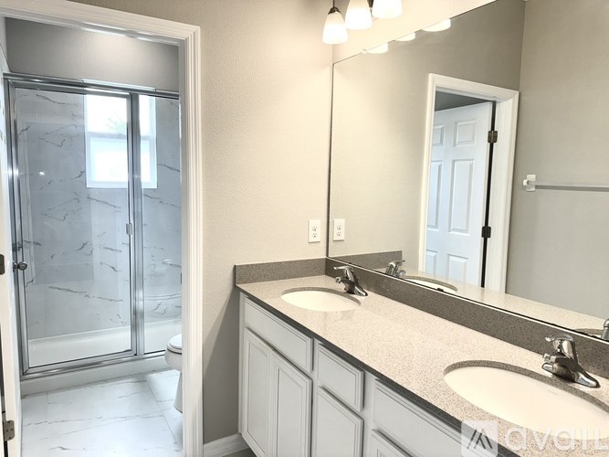A bathroom with a marble shower and a white door.