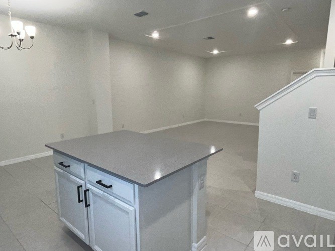 A kitchen island with a countertop and cabinets in a room with white walls.