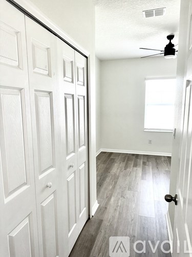 A hallway with white doors and a ceiling fan.
