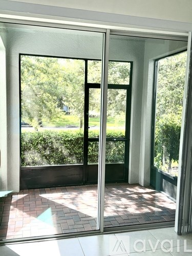 A glass door with a reflection of trees and a building.