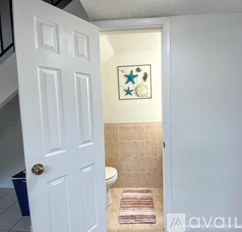A bathroom with a toilet and a decorative picture on the wall.