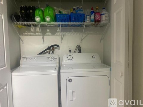 A laundry room with a washer and dryer and a shelf with cleaning supplies.