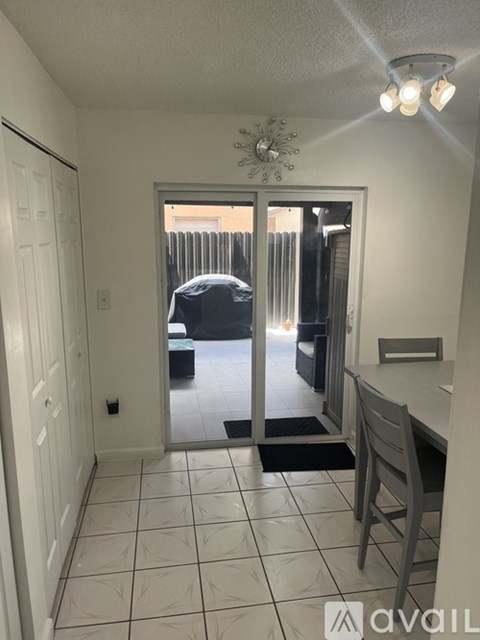 A kitchen with a table and chairs is visible through a glass door.