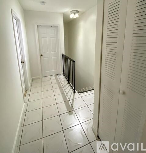 A hallway with a black railing and white walls.