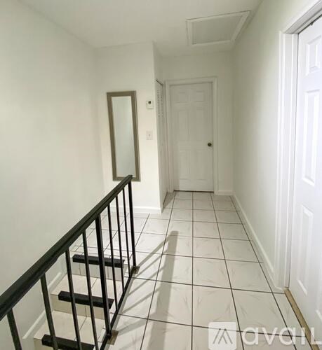 A hallway with a black railing and white walls.