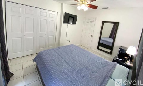 A bedroom with a bed, dresser, mirror, and a ceiling fan.